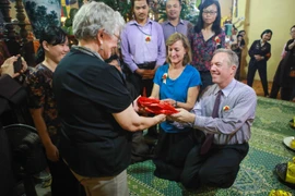 Ngài Ted Osius cùng chị gái mình trao tặng mẹ chiếc áo dài màu đỏ thể hiện sự biết ơn với mẹ mình và cầu mong người được sống lâu trăm tuổi. (Ảnh: Minh Sơn/Vietnam+)