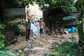 Ông Toàn lo lắng nhìn 'quả bom đất' có thể đổ ụp xuống căn nhà mỏng manh của ông bất cứ lúc nào. (Ảnh: Minh Sơn/Vietnam+)