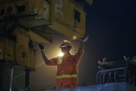 Có khoảng 15 công nhân phụ trách việc thi công và lắp đặt bao gồm công nhân điện, thợ lắp đặt và thi công để lao dầm, chưa kể một đội vận chuyển bên dưới. (Ảnh: Minh Sơn/Vietnam+)