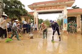 Lực lượng quân đội phối hợp cùng các giáo viên trường Tiểu học số 1 thị trấn Kiến Giang tổng vệ sinh môi trường sau khi lũ rút. (Ảnh: Vũ Sinh/TTXVN)
