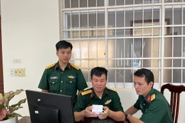 Thiếu tá Thiều Hữu Cường (ngồi giữa) với thiết bị IoT cảnh báo nguy cơ đột quỵ. (Ảnh: TTXVN phát)