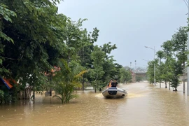 Lực lượng chức năng dùng xuồng cứu hộ giúp đỡ người dân trong vùng ngập lụt. (Ảnh: Chu Hiệu/TTXVN)