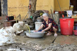 Người dân sinh sống trên 2 tuyến phố Thanh Niên và Trần Hưng Đạo, thành phố Yên Bái, dần trở lại cuộc sống thường nhật cho dù đường vẫn còn chưa hết ngập, chiều ngày 14/9. (Ảnh: Tuấn Anh/TTXVN)