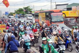 Người dân khó khăn khi di chuyển trên Quốc lộ 1, đoạn từ nút giao Nguyễn Văn Linh đến Nguyễn Hữu Trí. (Ảnh: Mạnh Linh/TTXVN)
