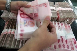 Kiểm tiền mệnh giá 100 nhân dân tệ tại một ngân hàng ở Bắc Kinh, Trung Quốc. (Ảnh: Getty Images/TTXVN)