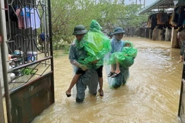 Lực lượng chức năng giúp người dân Chương Mỹ (Hà Nội) di chuyển đến những nơi an toàn. (Ảnh: TTXVN phát)