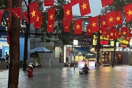 Người dân lội qua điểm ngập nước tại đường Thích Quảng Đức, thành phố Thủ Dầu Một, tỉnh Bình Dương. (Ảnh: TTXVN phát)