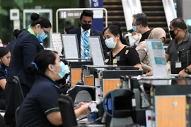 Hành khách làm thủ tục tại sân bay quốc tế Changi ở Singapore. (Ảnh: AFP/TTXVN)