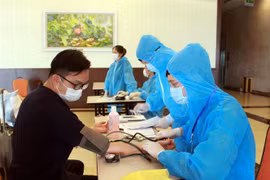 Nhân viên y tế hướng dẫn chuyên gia, lao động nước ngoài khai báo y tế và kiểm tra sức khỏe trước khi vào khách sạn cách ly. (Ảnh: TTXVN)