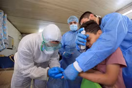 Nhân viên y tế lấy mẫu xét nghiệm COVID-19 cho một em nhỏ tại Baghdad, Iraq. (Ảnh: THX/TTXVN)