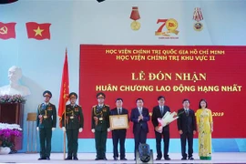 Bí thư Trung ương Đảng, Chủ tịch Hội đồng Lý luận Trung ương, Giám đốc Học viện Chính trị quốc gia Hồ Chí Minh Nguyễn Xuân Thắng trao Huân chương Lao động hạng Nhất của Chủ tịch nước tặng Học viện Chính trị khu vực II. (Ảnh: Thu Hoài/TTXVN)