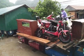 Người dân di chuyển đồ đạc, vật dụng của gia đình lên nhà phao, bè phao để tránh lũ. (Ảnh: Võ Dung/TTXVN)