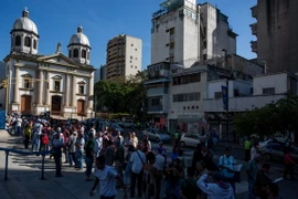 Người dân Venezuela xếp hàng chờ đổi tiền bên ngoài ngân hàng trung ương ở Caracas. (Nguồn: AFP/TTXVN)