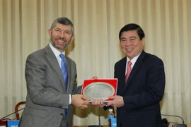 Chủ tịch Ủy ban Nhân dân Thành phố Hồ Chí Minh Nguyễn Thành Phong tặng quà lưu niệm cho Thứ trưởng Bộ Phát triển Kinh tế Italy Ivan Scalfarotto. (Ảnh: Thanh Vũ/TTXVN)
