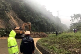 Lực lượng chức năng xử lý hiện trường sạt lở cho các phương tiện qua lại. (Ảnh: Quang Thái/TTXVN)