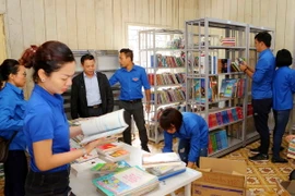 Đoàn viên thanh niên TTXVN chuyển sách lên giá tại thư viện trường Phổ thông Dân tộc bán trú Tiểu học và THCS Phình Hồ. (Ảnh: Thành Đạt/TTXVN)