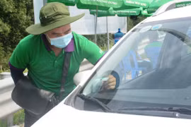 Nhân viên một nhà cung cấp dịch vụ thu phí không dừng dán thẻ định danh cho phương tiện. (Ảnh: Việt Hùng/Vietnam+)