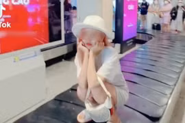 Một cô gái leo lên băng chuyền hành lý ngồi xổm để quay clip đăng TikTok.