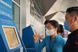 Nhân viên Vietnam Airlines hướng dẫn giúp hành khách làm thủ tục trực tuyến tại Kios check-in online ở một sân bay. (Ảnh: CTV/Vietnam+)