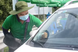 Nhân viên nhà cung cấp dịch vụ thu phí không dừng VETC dán thẻ định danh Etag cho phương tiện. (Ảnh: Việt Hùng/Vietnam+)