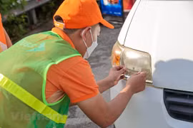 Nhân viên của Công ty cổ phần Giao thông số Việt Nam (VDTC) dán thẻ thu phí không dừng cho phương tiện. (Ảnh: Minh Sơn/Vietnam+)