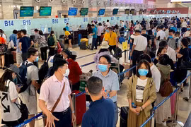 Hành khách xếp hàng chờ làm thủ tục lên máy bay. (Ảnh: CTV/Vietnam+)