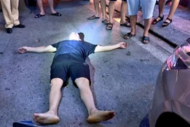 Tài xế Nguyễn Văn Quang nằm "ăn vạ" gây cản trở giao thông, an ninh công cộng. (Ảnh: TTXVN phát)