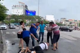 Dù phóng viên T.T.C đã nằm gục trên lòng đường, hai đối tượng này vẫn tiếp tục tấn công phóng viên. (Ảnh cắt từ clip)