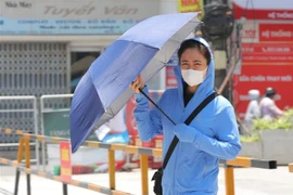 Người dân trang bị nhiều đồ chống nắng, nóng khi phải di chuyển ngoài trời. (Ảnh: Hoàng Hiếu/TTXVN)