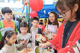 Các em học sinh và phụ huynh chăm chú theo dõi cách pha trà. (Ảnh: Phạm Mai/Vietnam+)
