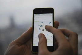 Một khách hàng sử dụng điện thoại di động để gọi dịch vụ xe của Uber . (Nguồn: AFP/TTXVN)