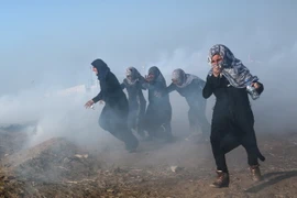 Người biểu tình Palestine chạy trốn khỏi khu vực hơi cay trong cuộc xung đột với binh lính Israel tại biên giới Gaza-Israel ngày 15/5. (Nguồn: EPA/TTXVN)