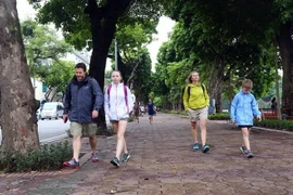 Các vị khách du lịch nước ngoài cũng chuẩn bị cho mình áo khoác mỏng để đón gió lạnh tại hồ Hoàn Kiếm (Hà Nội). (Ảnh: Danh Lam/TTXVN)