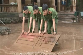 Hơn 100 cán bộ chiến sỹ công an được huy động giúp trường học dọn dẹp bùn đất. (Ảnh: Khiếu Tư/TTXVN)