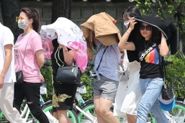 Khách du lịch dùng khăn và áo để che chắn tránh nắng tại Seoul, Hàn Quốc. (Ảnh: Yonhap/TTXVN)