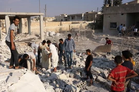  Tìm kiếm các nạn nhân dưói những đống đổ nát sau vụ không kích tại tỉnh Idlib. (Nguồn: AFP/TTXVN)