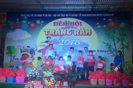 Đại diện Ủy ban Nhân dân xã Nam Phương Tiến tặng quà động viên các em nhỏ khuyết tật. (Ảnh: Nguyễn Cúc/TTXVN) 