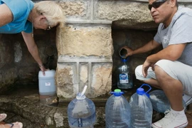 Người dân hứng nước từ mạch nước ngầm ở St. James, Cape Town, Nam Phi. (Nguồn: AFP/TTXVN)