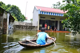 Người dân chèo thuyền ngay ở sân nhà mình. (Ảnh: Quốc Dũng/Vietnam+)