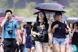 Người dân che ô để tránh nắng tại Tokyo, Nhật Bản. (Ảnh: Kyodo/TTXVN)