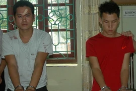 Hai đối tượng cùng tang vật vụ án tại cơ quan điều tra. (Nguồn: TTXVN)