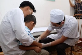 Bác sỹ Bệnh viện Da liễu Trung ương khám cho trẻ nhỏ mắc bệnh sùi mào gà. (Ảnh: Phạm Kiên/TTXVN)