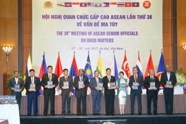 Đại biểu nâng bản cam kết về Kế hoạch hành động bảo vệ Cộng đồng ASEAN chống lại hiểm họa ma túy cho giai đoạn 2016-2025. (Ảnh: Doãn Tấn/TTXVN)