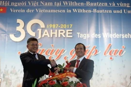 Ông Lê Thanh Hải (trái) - Bí thư thứ nhất Đại sứ quán Việt Nam tại Đức​ - tặng hoa chúc mừng tại buổi gặp mặt. (Ảnh: Thanh Bình/TTXVN)