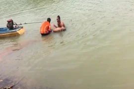 Lực lượng chức năng phối hợp với người dân vớt thi thể nam thanh niên bị đuối nước. (Ảnh: TTXVN phát)