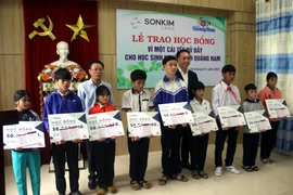 Ông Lê Văn Nhi, Tổng Biên tập Báo Quảng Nam cùng lãnh đạo Công ty SonKim Land trao học bổng cho các em học sinh. (Ảnh: Trịnh Bang Nhiệm/TTXVN)