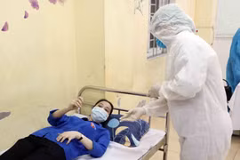 Cán bộ y tế kiểm tra sức khoẻ ban đầu cho thí sinh có biểu hiện ho sốt bất thường để có hướng xử lý tiếp theo. (Ảnh: Thanh Tùng/TTXVN) 