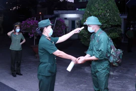 Các thanh niên lên đường nhập ngũ được kiểm tra thân nhiệt, rửa tay sát khuẩn tại điểm giao nhận quân tổ chức tại Quận 5, Thành phố Hồ Chí Minh. (Ảnh: Xuân Khu/TTXVN)
