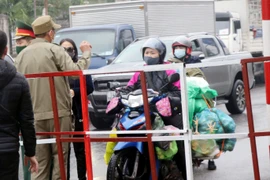 Người dân mang nhu yếu phẩm đến chốt kiểm dịch để cung cấp cho người thân trong vùng phong tỏa. (Ảnh: Văn Đức/TTXVN)