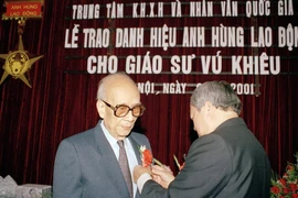 Ngày 2/1/2001, tại Hà Nội, Trung tâm Khoa học xã hội và Nhân văn quốc gia tổ chức lễ trao tặng danh hiệu Anh hùng Lao động thời kỳ đổi mới cho Giáo sư Vũ Khiêu. Trong ảnh: Chủ nhiệm Văn phòng Quốc hội Vũ Mão gắn huy hiệu Anh hùng Lao động thời kỳ đổi mới 